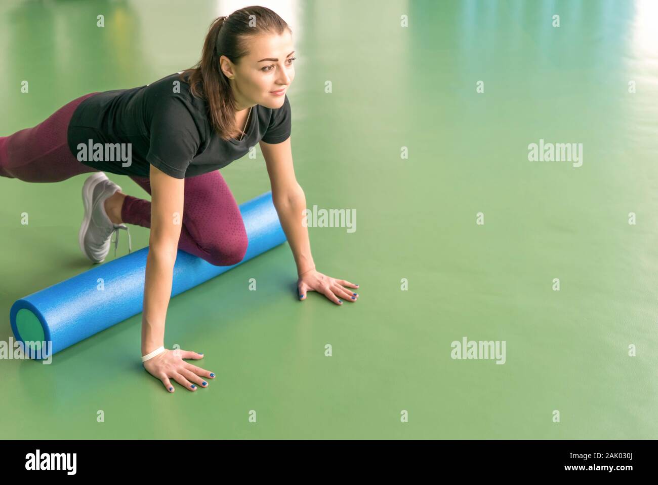Attractive female doing foam roller exercise and posing in modern ...