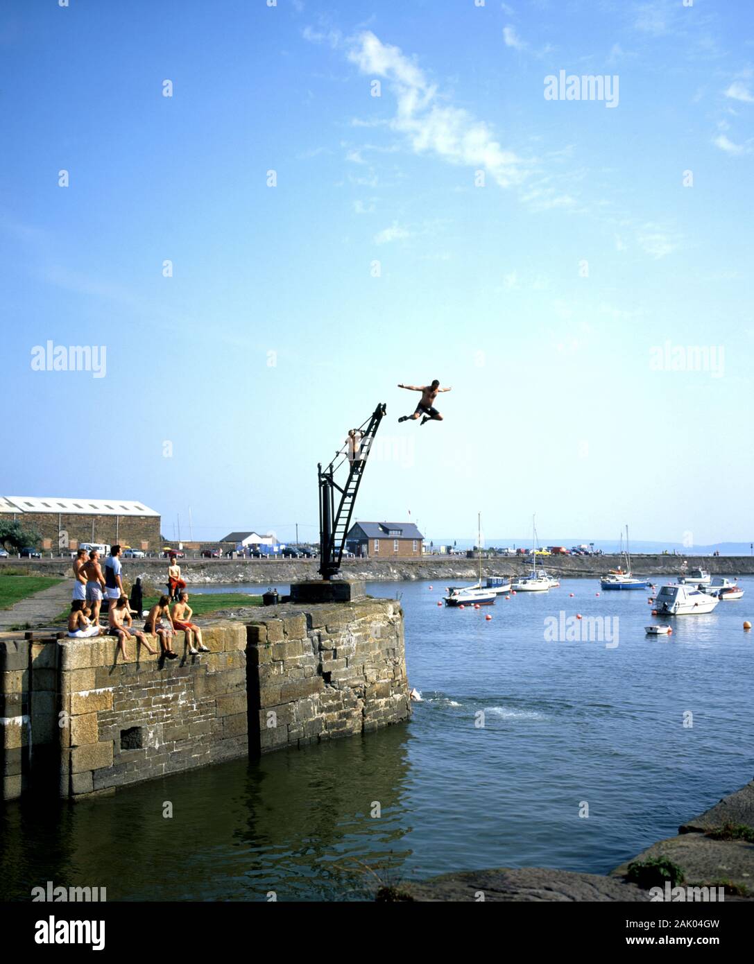 Young men leaping from crane into Bury Port Docks near Llanelli, Carmarthenshire, West Wales. Stock Photo