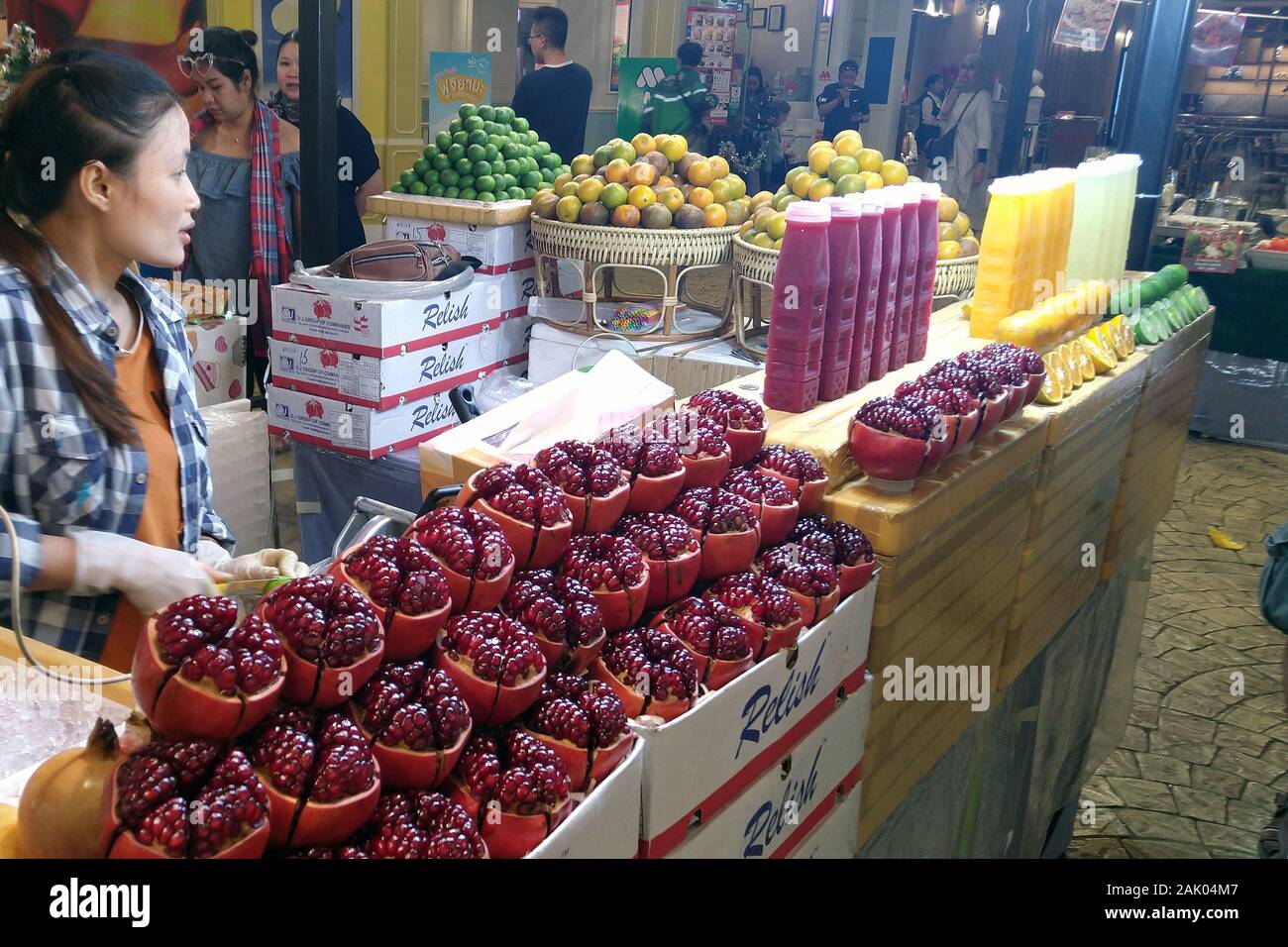 Woman sells pomegranate, orange and lime juices on street market at night. Stock Photo