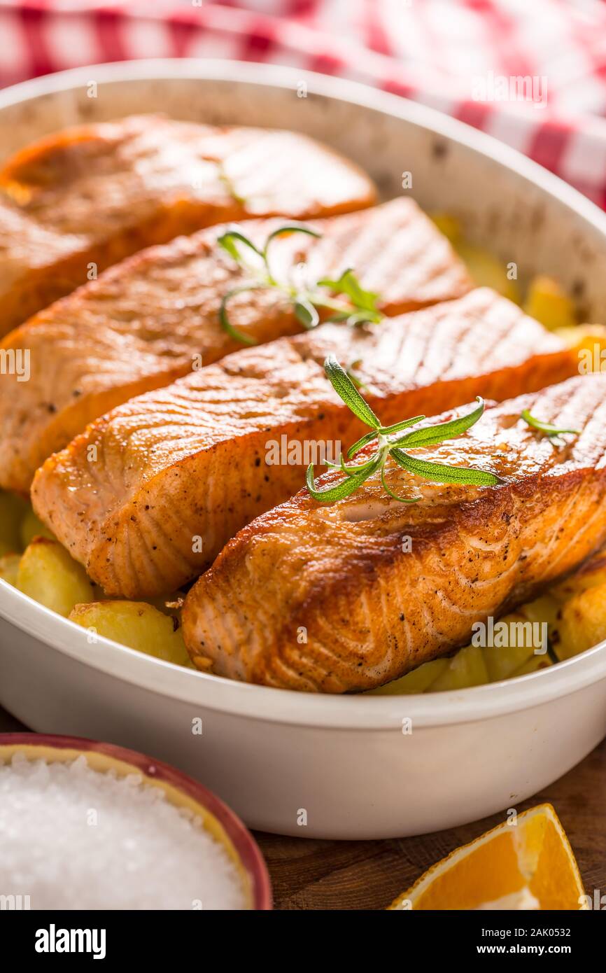 Baked salmon fillets with potatoes and herbs in a baking dish Stock Photo