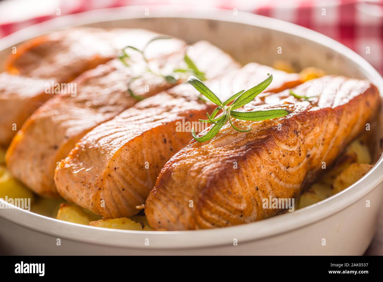 Baked salmon fillets with potatoes and herbs in a baking dish Stock Photo