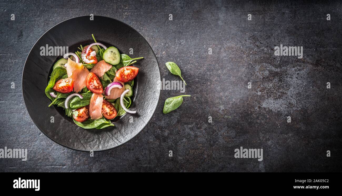 Salmon salad with vegetable in plate on dark kitchen table - Top of view Stock Photo