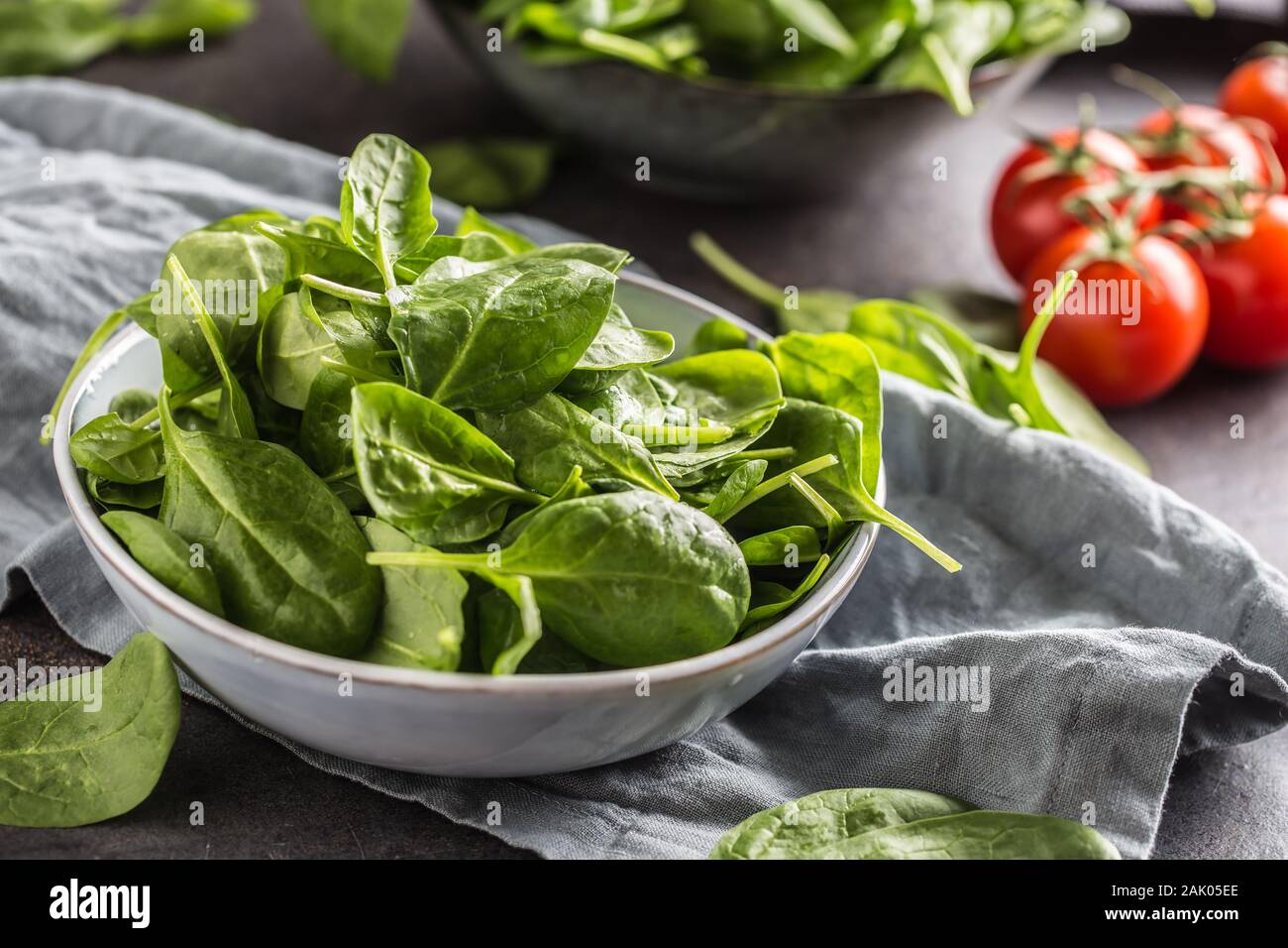 Fresh baby spinach in bowl on dark kitchen table Stock Photo