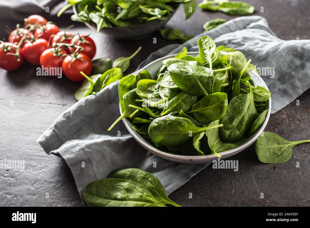 Fresh baby spinach in bowl on dark kitchen table Stock Photo