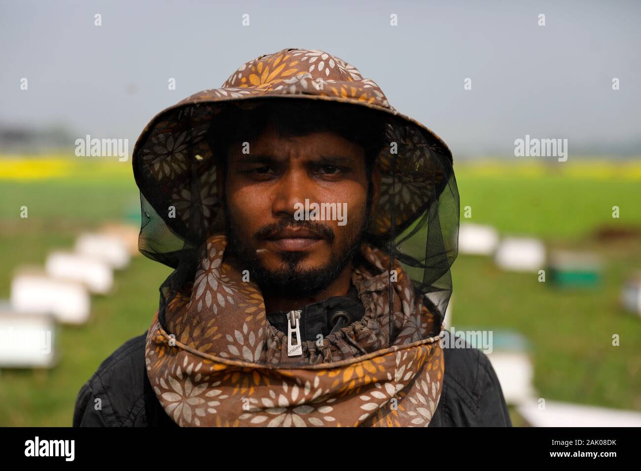 A Bangladeshi farmer Shahidul poses for a photo at a mustard field in Munshiganj, Dhaka.According to the Bangladesh Institute of Apiculture (BIA), around 25 thousand cultivators including 1,000 commercial agriculturists produce at least 1500 tons of good quality honey a year across the country. Stock Photo