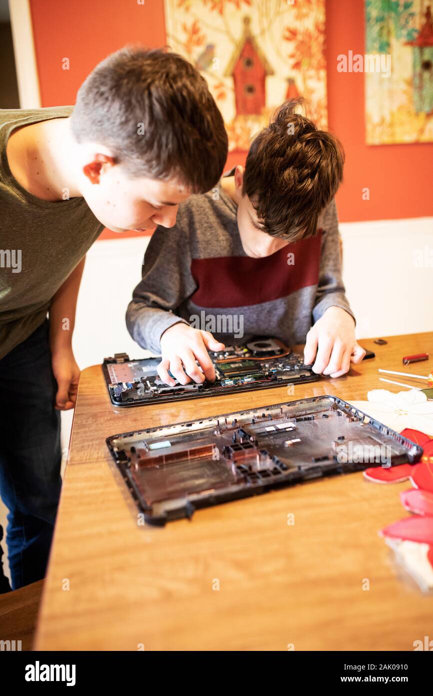 Two teenage boys take apart an old laptop computer. Stock Photo