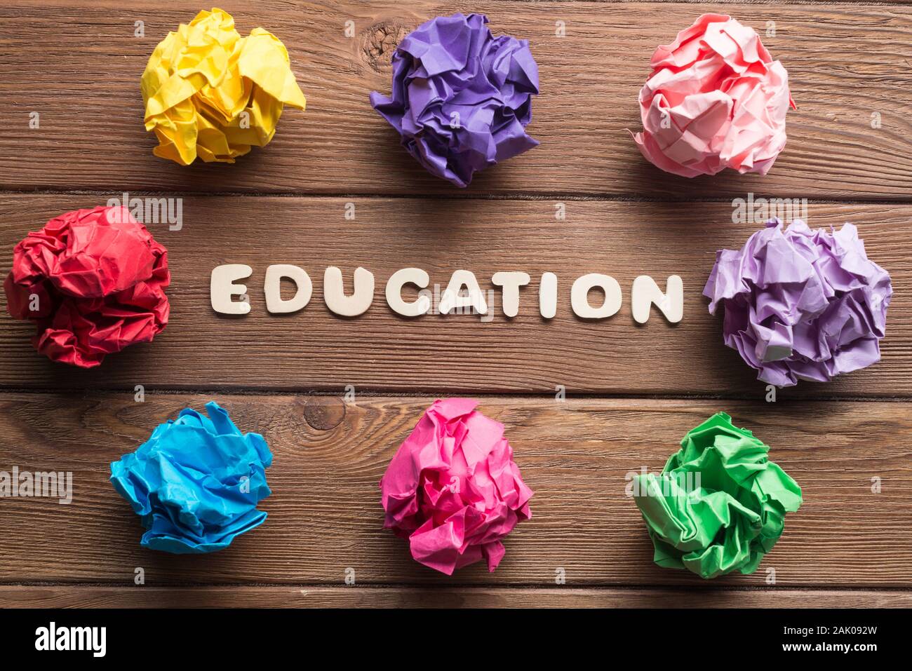 Education word and colorful crampled paper ball placed in circle on wooden table Stock Photo