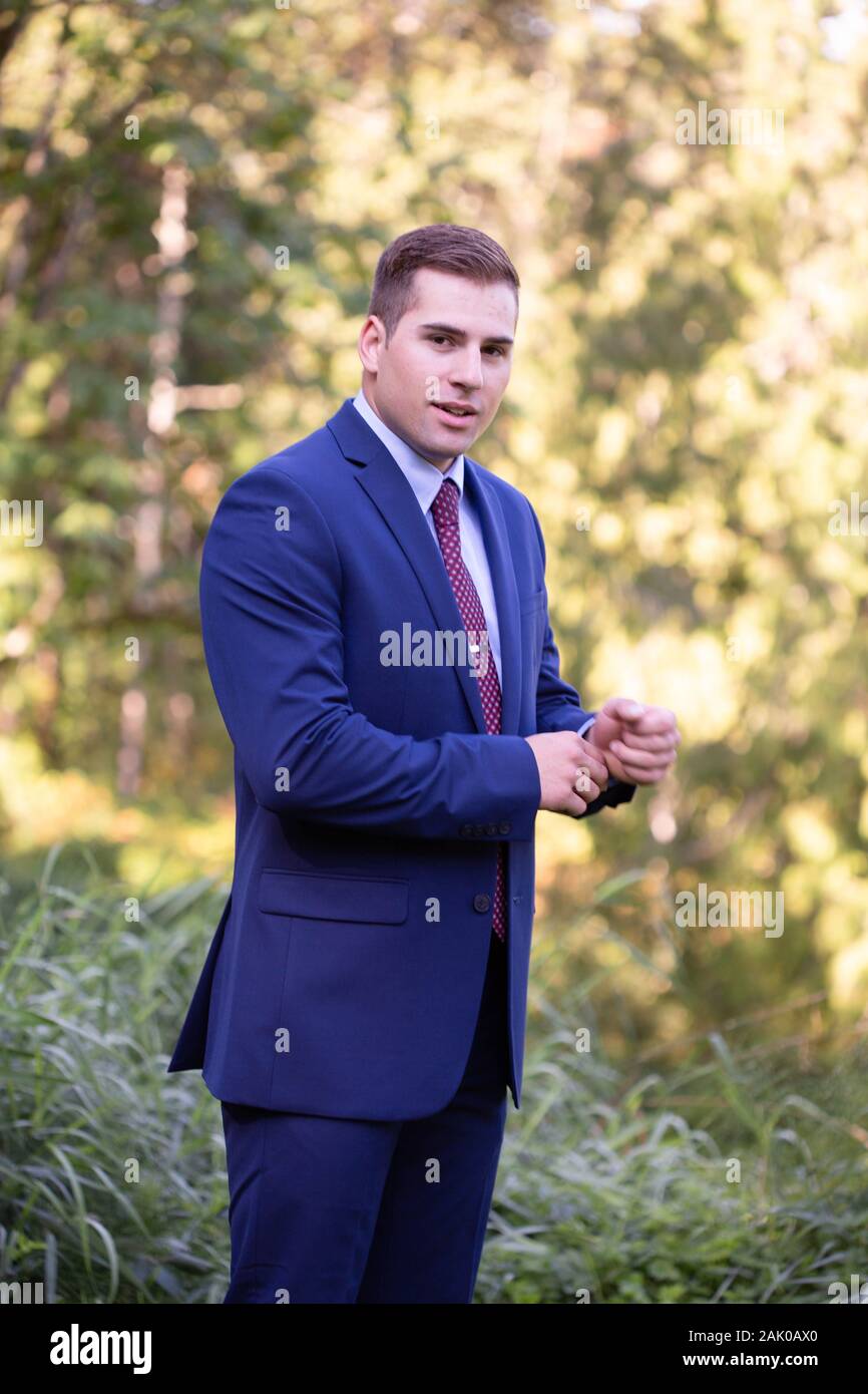 Confident young man smiles at the camera while standing outside. Stock Photo