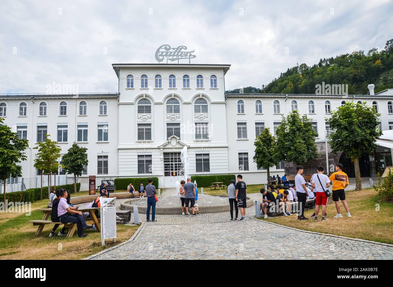 Broc, Switzerland - July 27, 2019: Visitors waiting in front of the building of the famous Cailler chocolate factory. People in the courtyard of the areal. Tour and museum. Swiss chocolate. Stock Photo