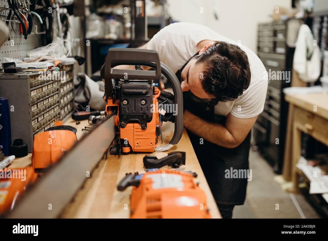 Man in workshop fixing chainsaw Stock Photo - Alamy