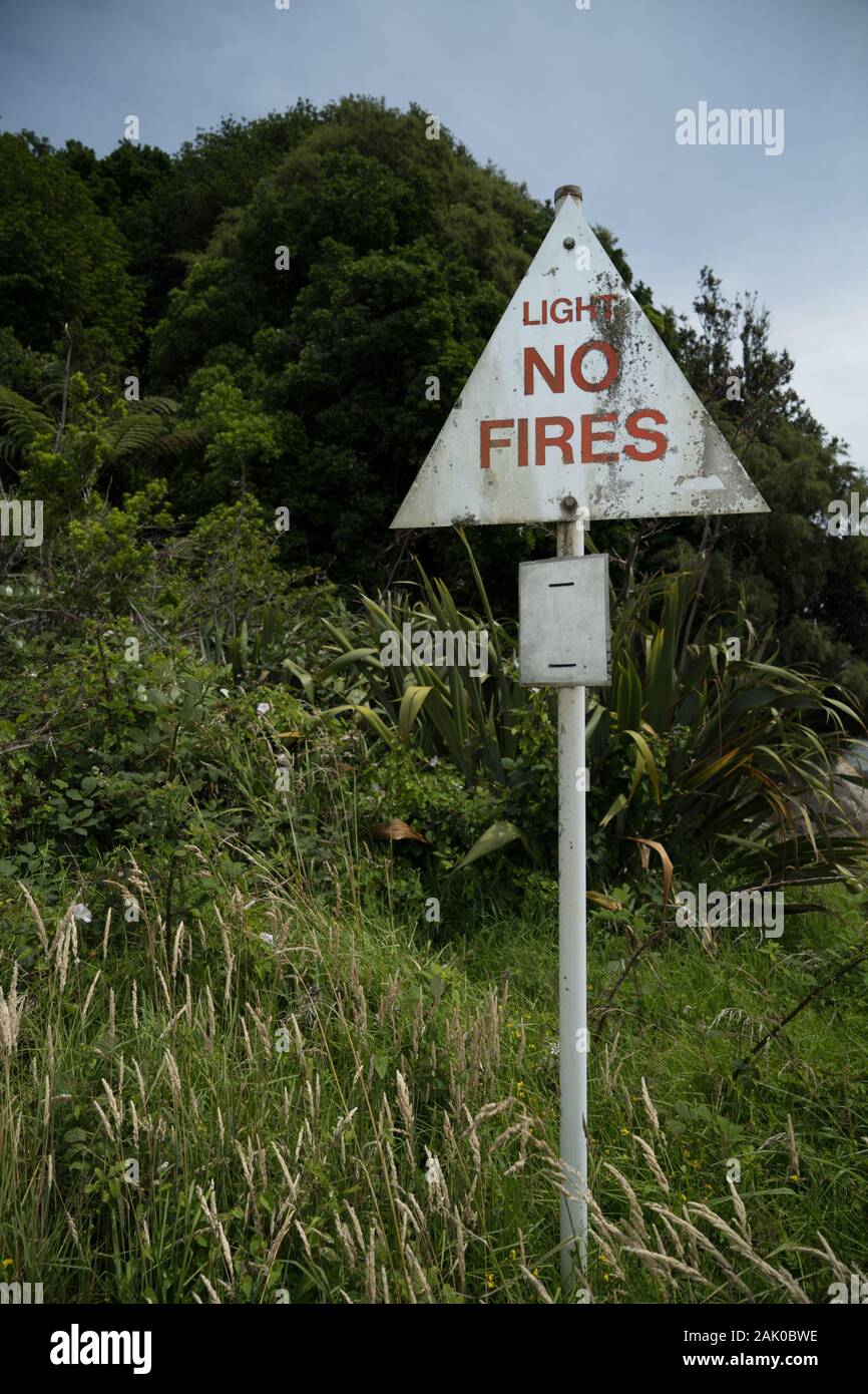 Three sisters car park, Tongoporutu, Northern Taranaki,  New Zealand. A weathered white and red Light No Fires warning sign forest, bush, fire season Stock Photo