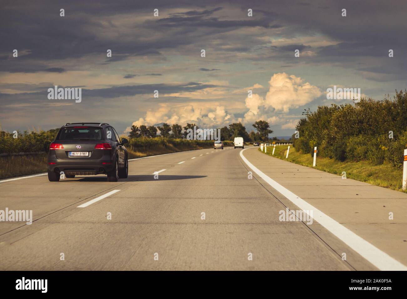 car driving on the highway to the horizon, in nature, on a background of blue sky with clouds, sunset Stock Photo