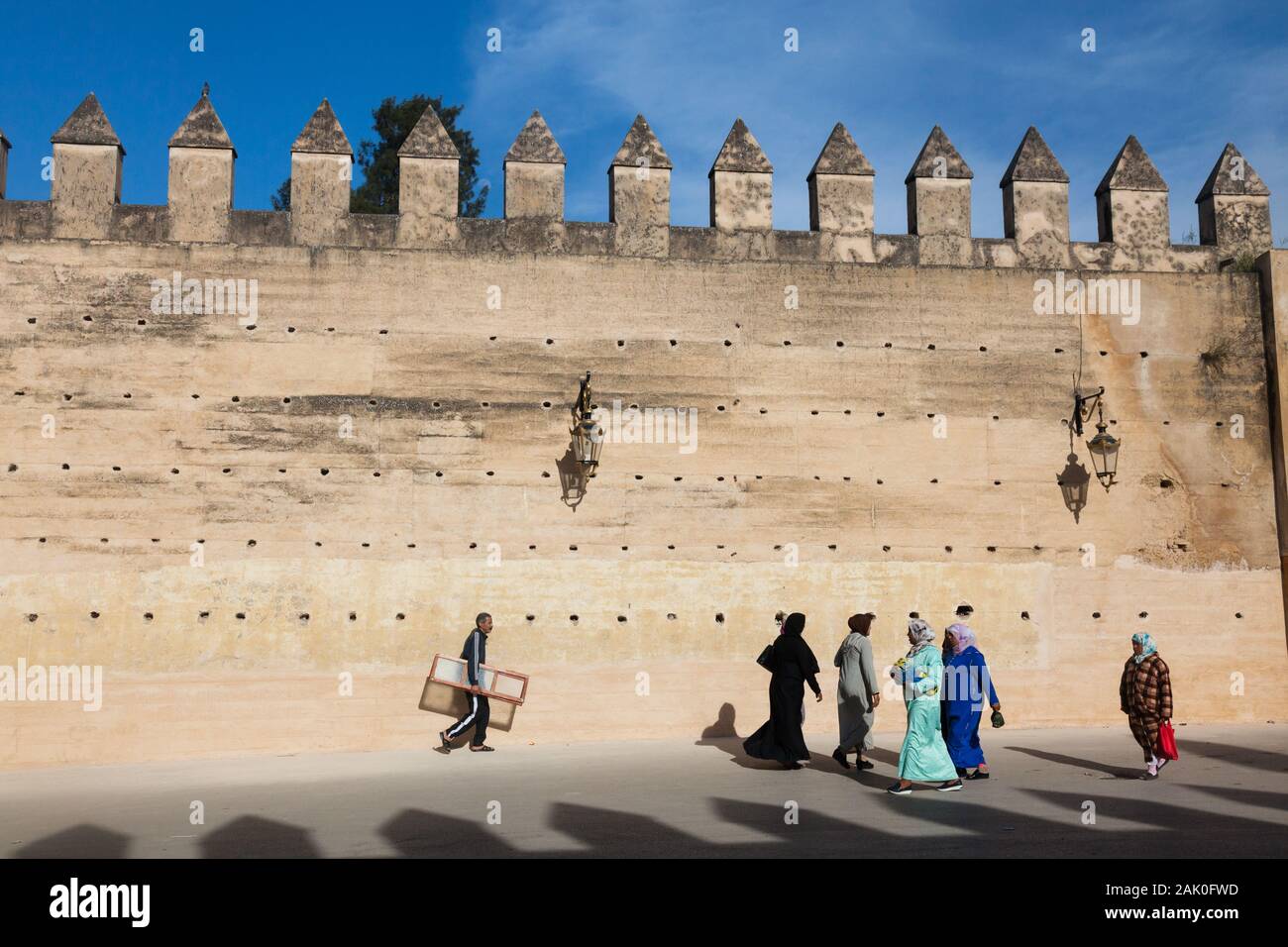 Pedestrians in afternoon scenery of rammed earth city walls with crenels and merlons in area of Bab Mechouar and Bab Dekkakin in Fes (Fez), Morocco Stock Photo