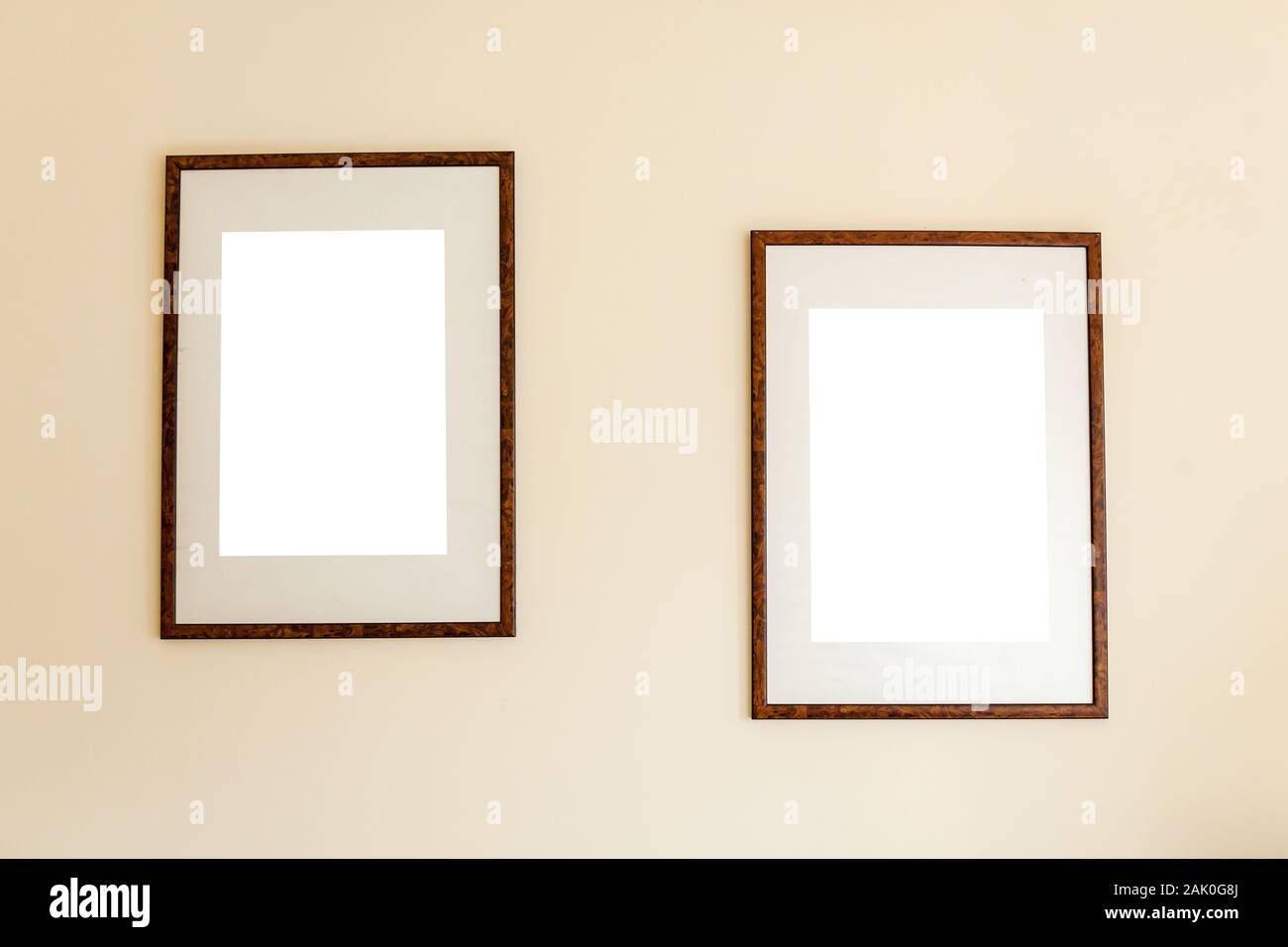Minimalist empty wooden frames hanging out on a background of a beige wall. Stock Photo