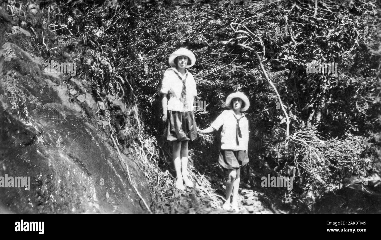 Two young white Caucasian women wearing wide brimmed hats, stand beside a waterfall at Refuge Bay, in Ku-ring-gai Chase National Park,  New South Wales, Australia in 1922 Stock Photo