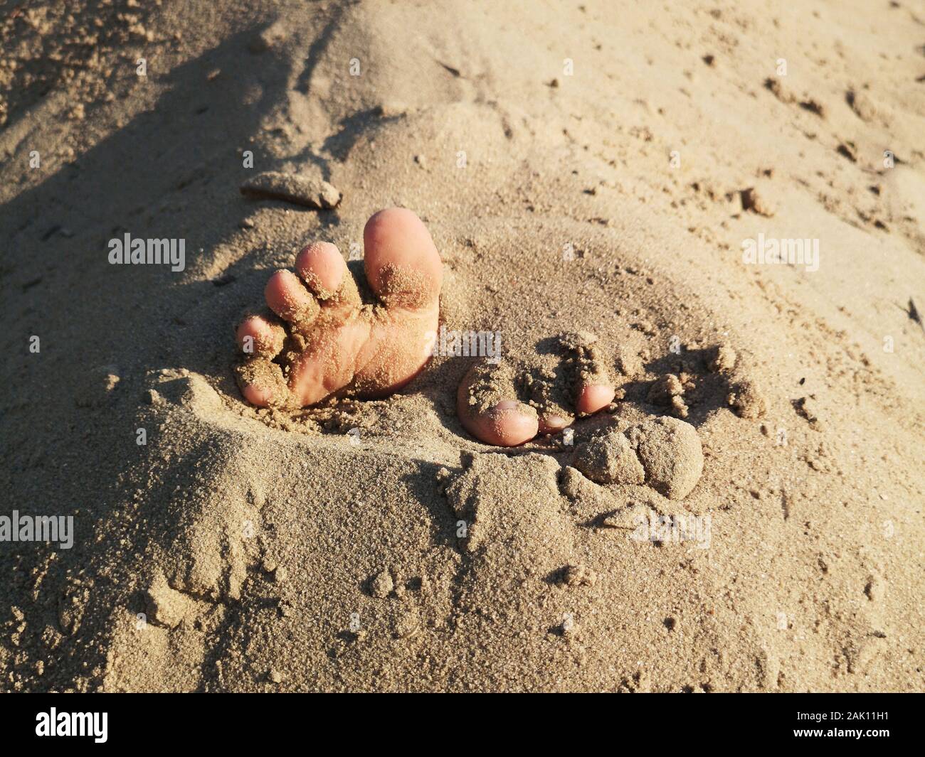 .Baby fingers in the sandStuck baby feet in sand on sea beach on sunny ...