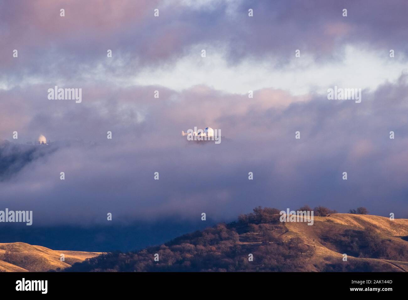 Storm clouds covering the top of Mount Hamilton, with Lick Observatory peeking through them; San Jose, South San Francisco Bay Area, California Stock Photo