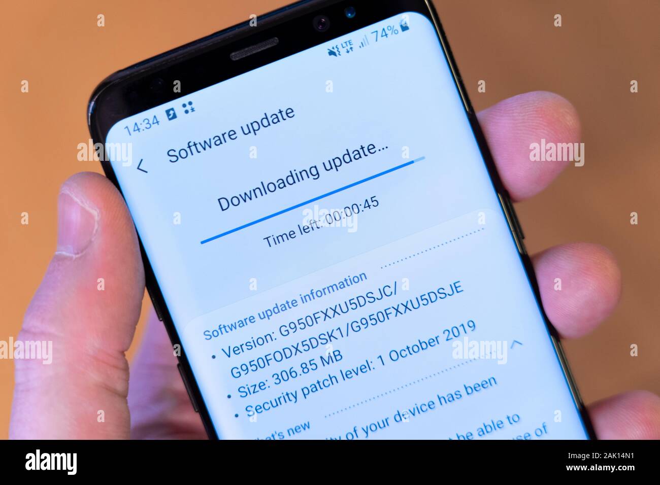A Galaxy S8 smartphone held in a man's hand and downloading an Android operating system update and security patch Stock Photo