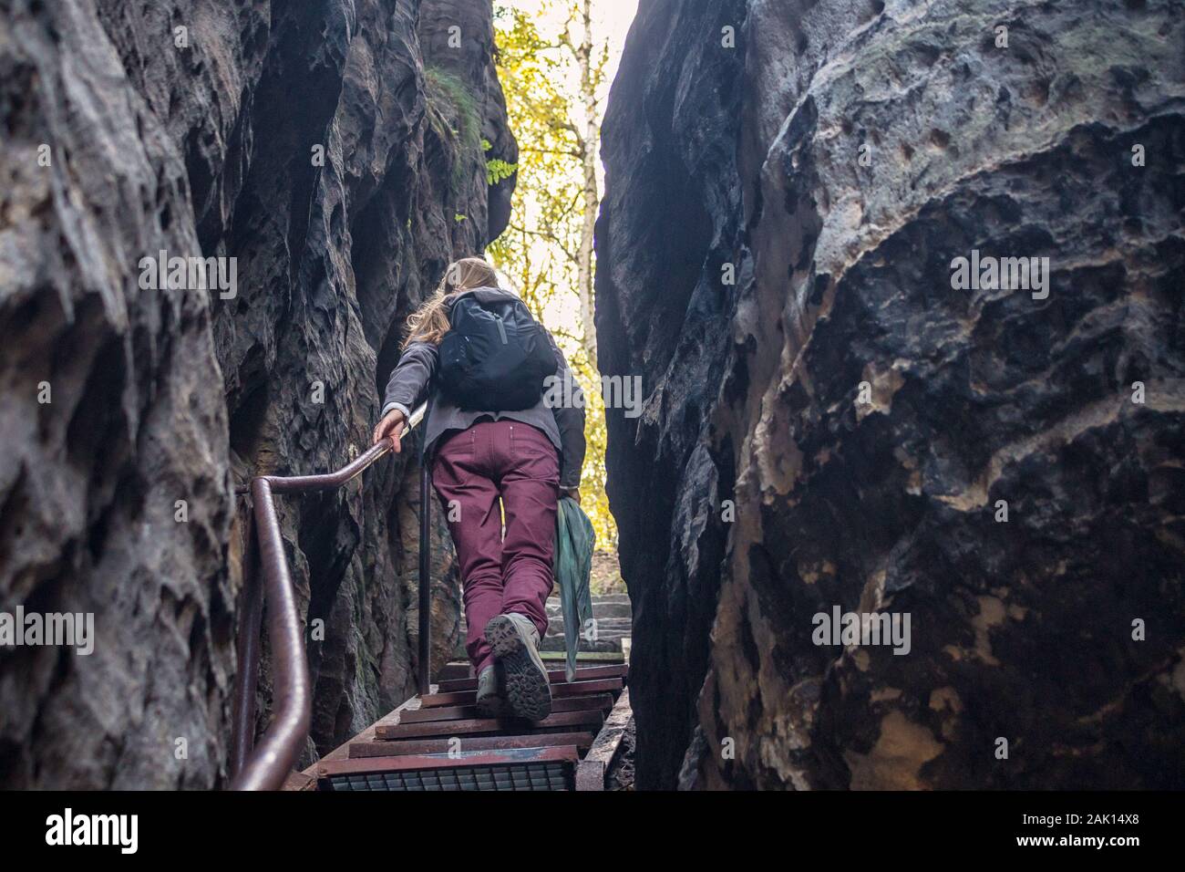 woman climbs the stairs through a rift in the rocks Stock Photo