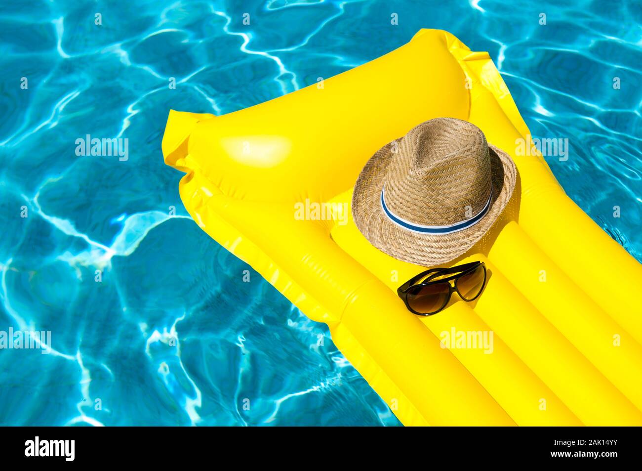 Hat and sunglasses resting on bright yellow inflatable raft floating in ...