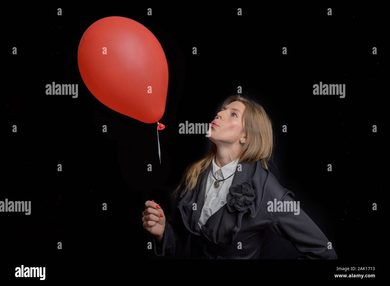 Business woman in a suit blows on a balloon Stock Photo
