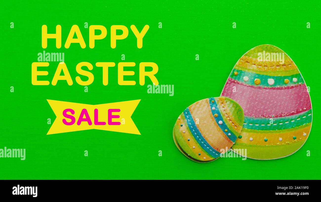 two colored Easter eggs with happy easter sale message on a green background Stock Photo