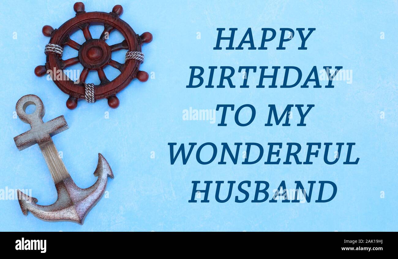 ship anchor and wheel laying on a blue background with happy birthday to my wonderful husband in blue text Stock Photo