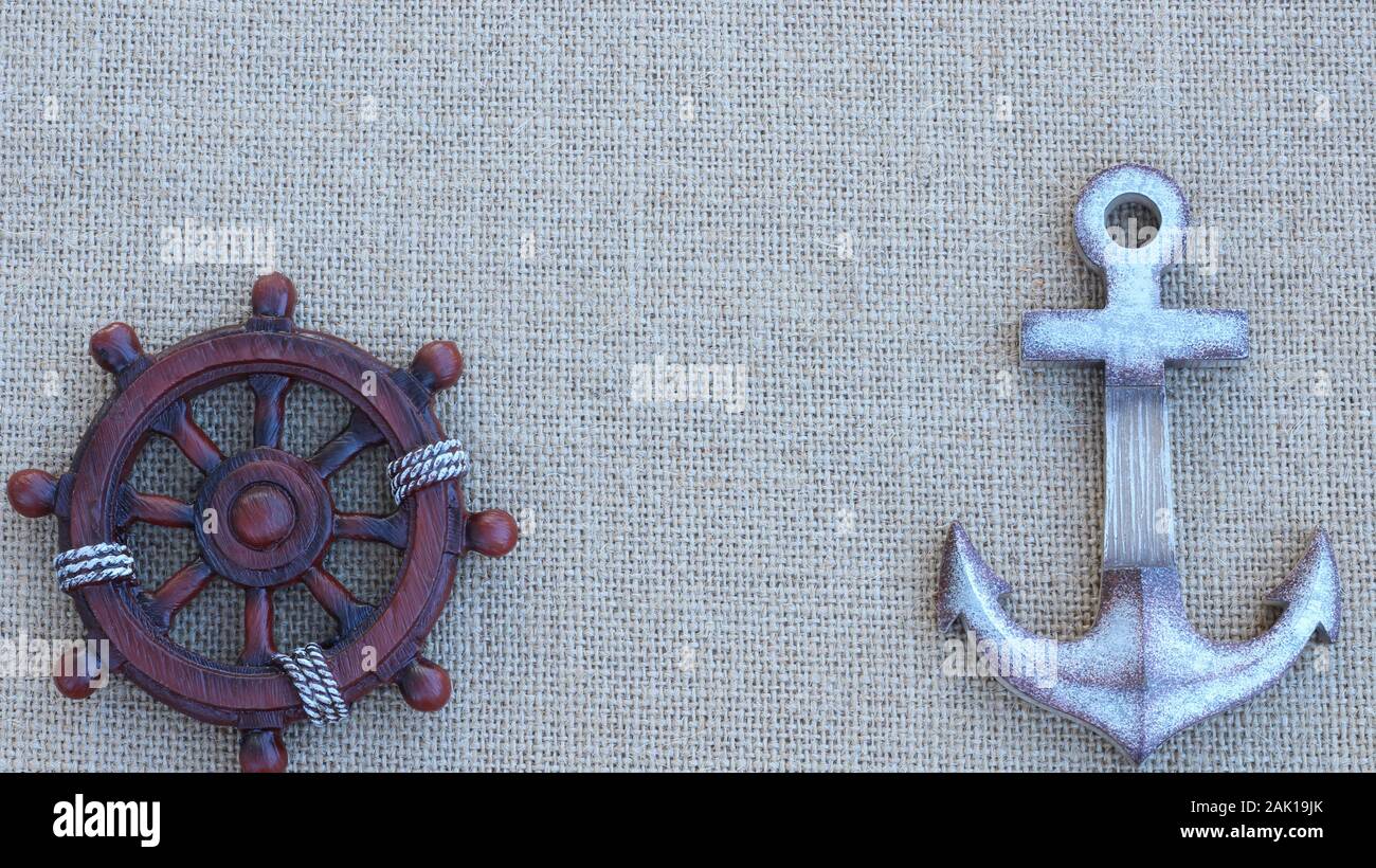 ship wheel and anchor laying on a textured nautical background with copy space Stock Photo