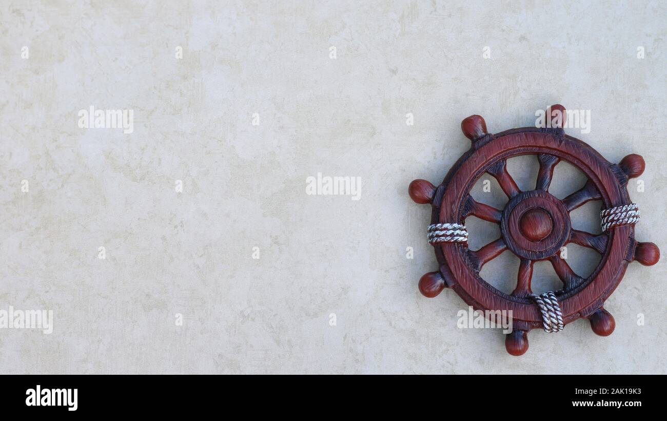 wooden ship wheel isolated on a textured nautical background with writing space Stock Photo