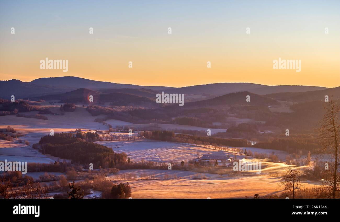 sunrise in the mountains - winter hilly landscape with forests, trees and meadows (with hoarfrost and snow) Stock Photo
