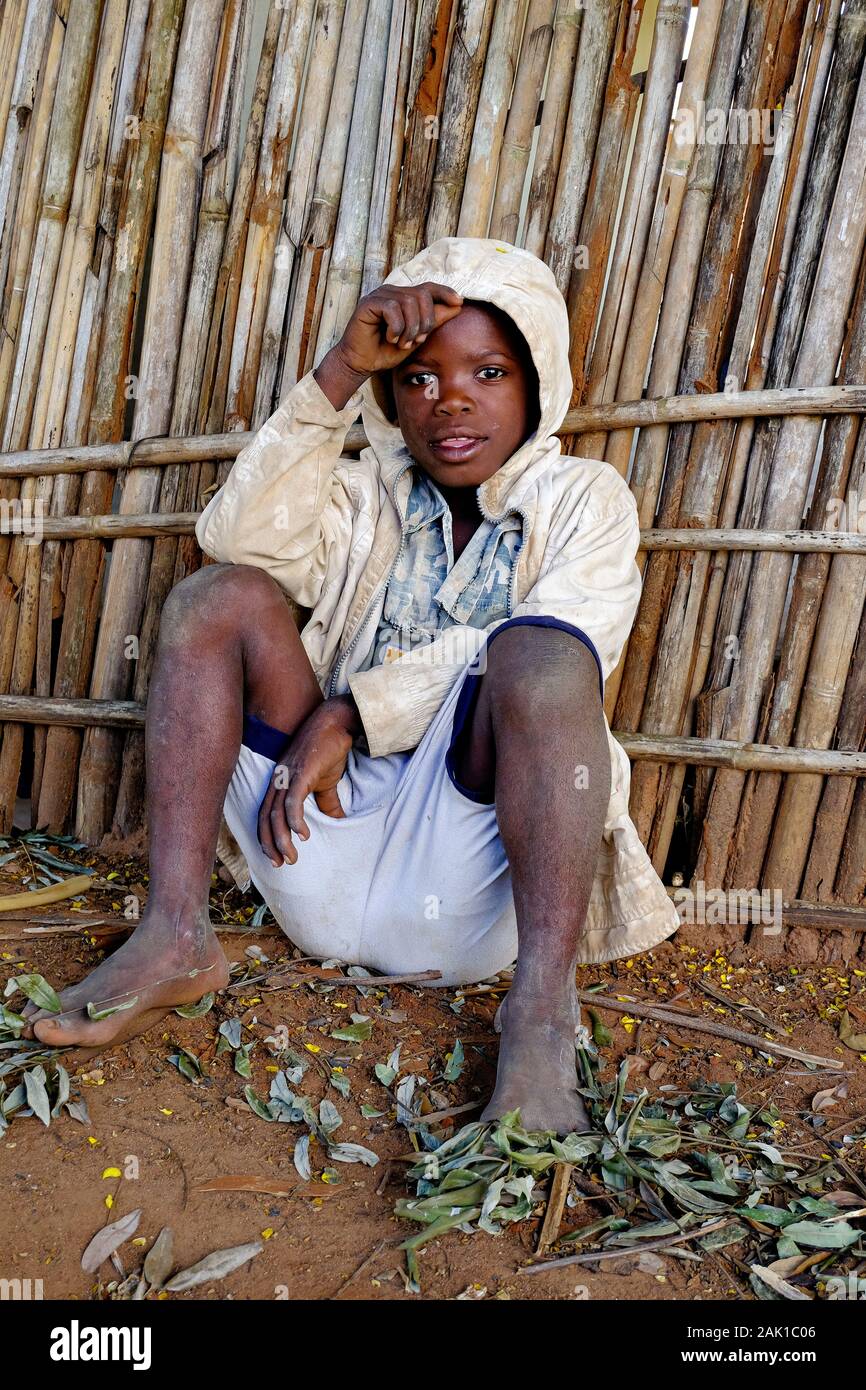 One african boy sitting on the floor next to a fence Stock Photo