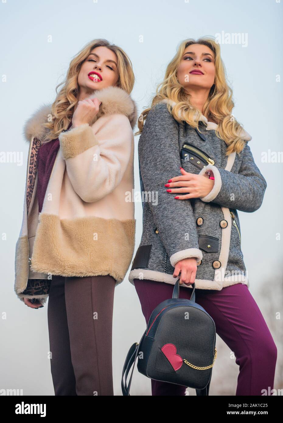 Stay warm and fashionable. Women wear furry coats. Winter clothes. Wardrobe  for cold weather. Girls enjoy cozy fancy chic coats. Natural wool sheepskin  coats. Fur shop. Backpack fashion accessory Stock Photo 