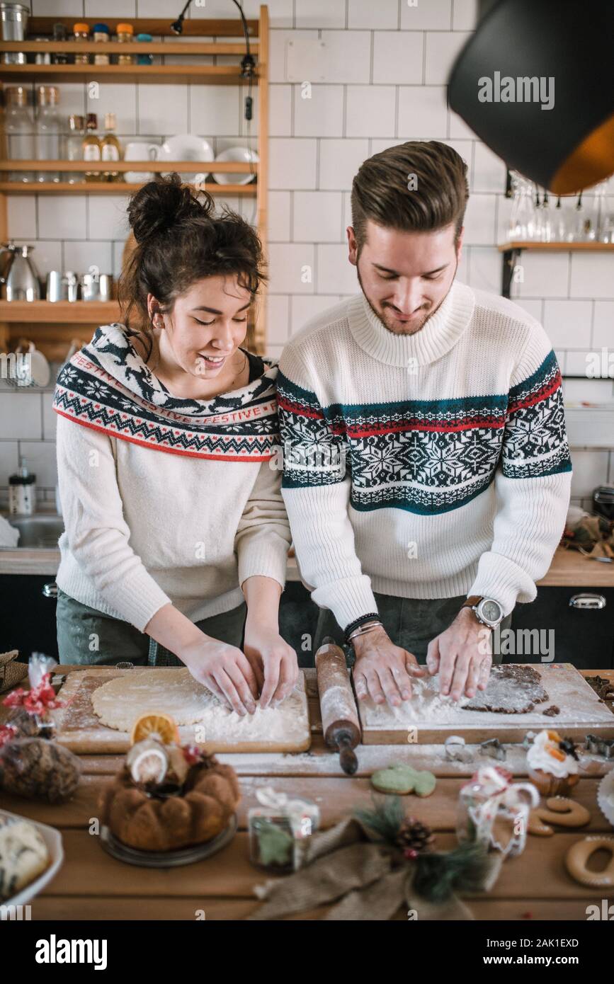 Friends in Christmas sweater make dough in the kitchen. Stock Photo