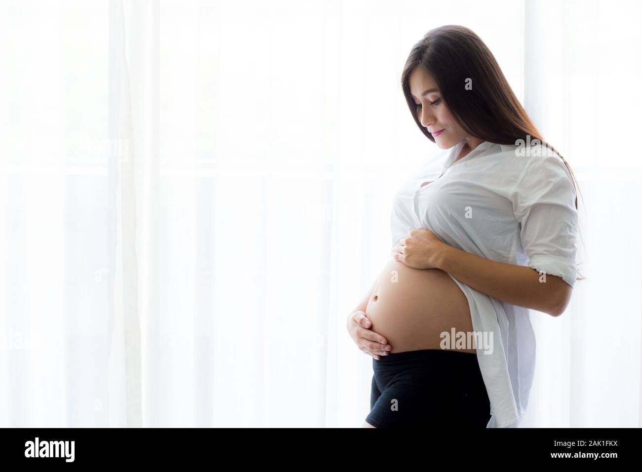 Pregnant belly with hand holding care. Beautiful young woman pregnant - Love Concept. Stock Photo