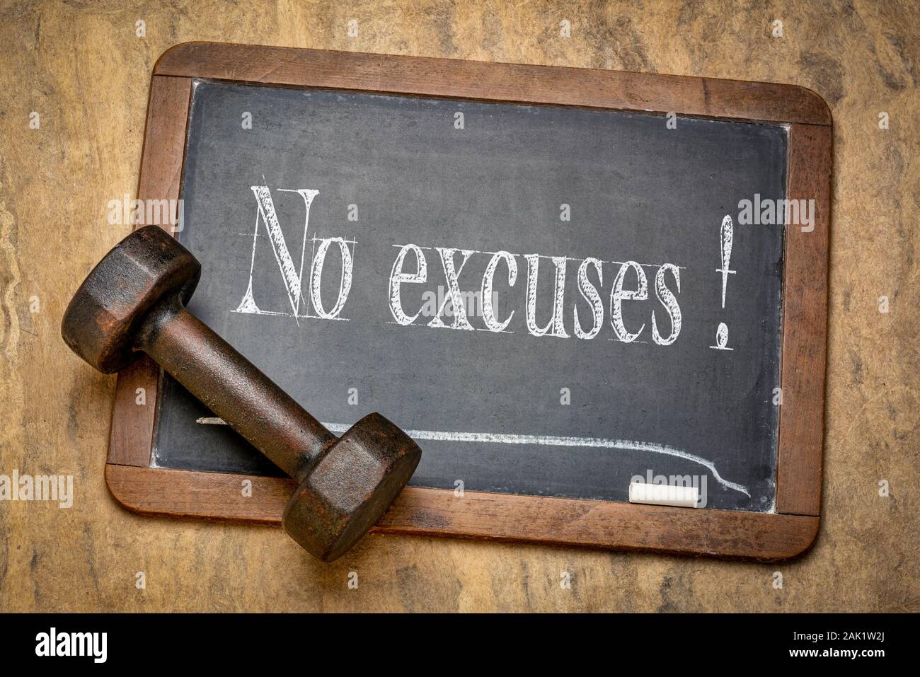 no excuses motivational reminder - white chalk text on a slate blackboard with a dumbbell, fitness, persistence and determination concept Stock Photo