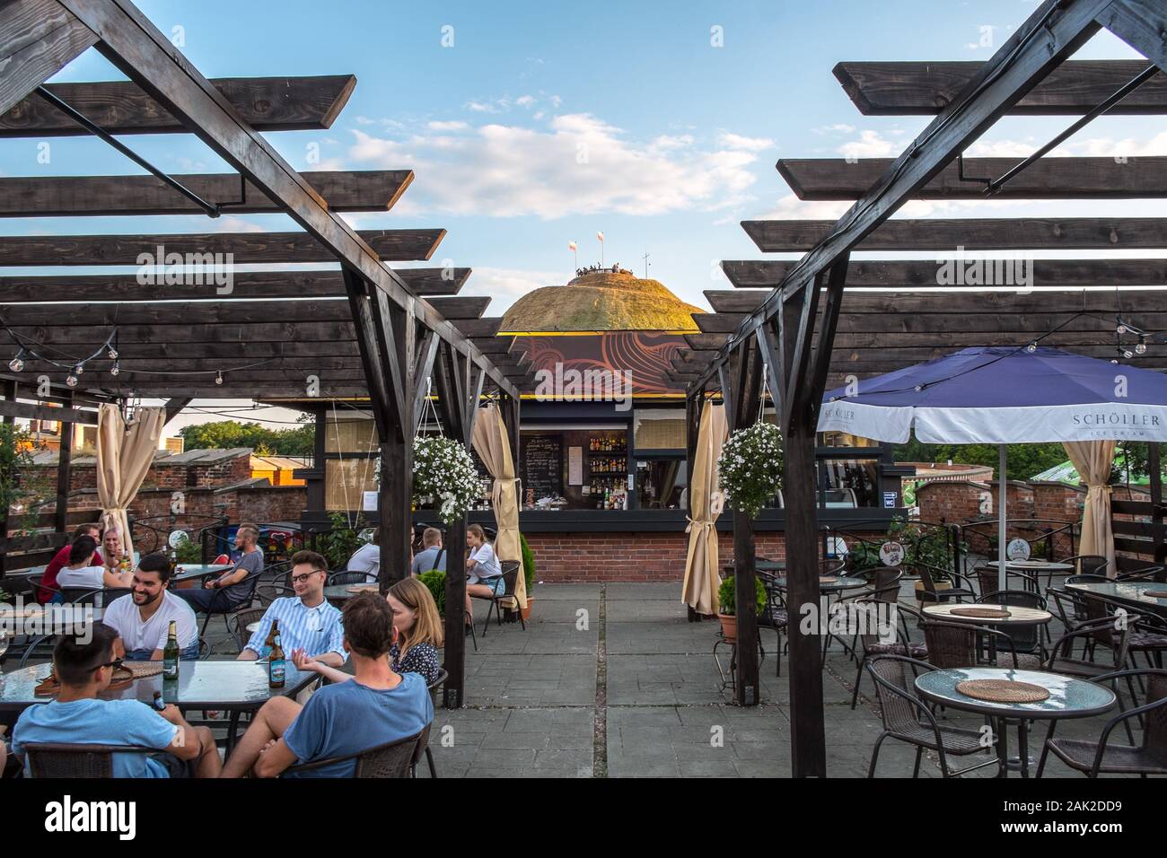 Tourists sit in a café beneath Kosciuszko Mound in Kraków, Poland, on a summer evening Stock Photo