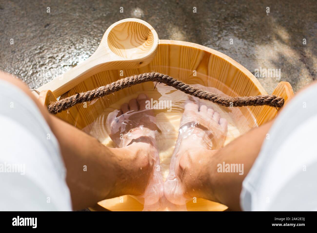 Legs soak in hot spring water on a wooden pail for therapeutic uses, Sembawang Hot Spring park, Singapore Stock Photo