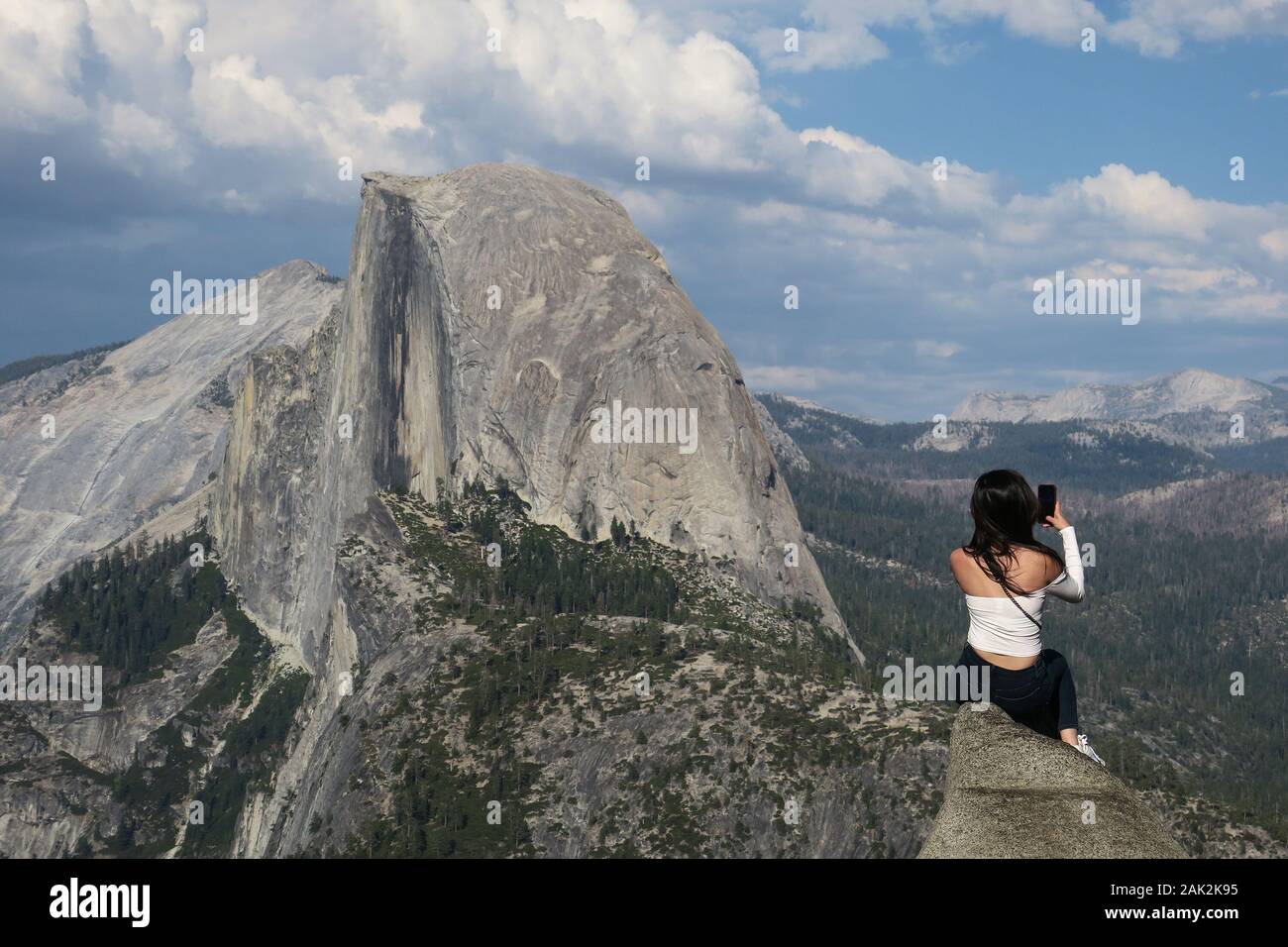 Lone traveler woman taking daring selfie with Half Dome view - Glacier Point, Yosemite Stock Photo