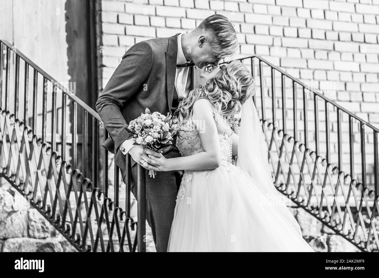 bride and groom standing on the porch of a brick house. black and white ...