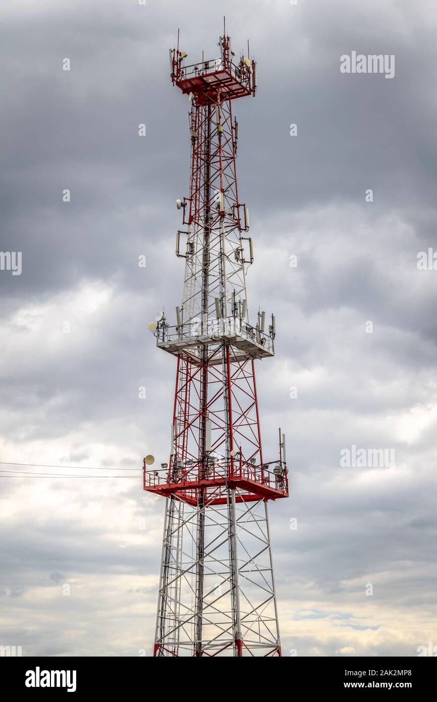 A large red and white cell tower against a gray cloudy sky Stock Photo -  Alamy