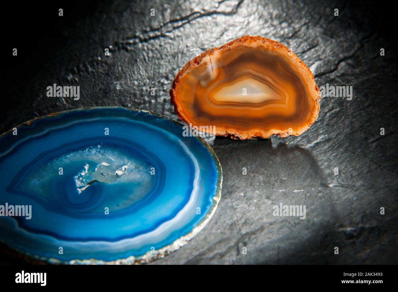 Studio shot of a thin polished disc of a round agate with blue circular banded grain and middle druse (hole) surrounded by crystalline structures. Stock Photo