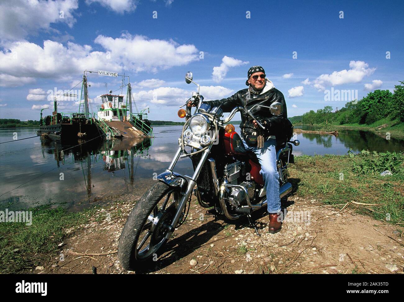 View of a biker and in the background a ferry which crosses the river Nemunas, Lithuania. (Undated picture) | usage worldwide Stock Photo