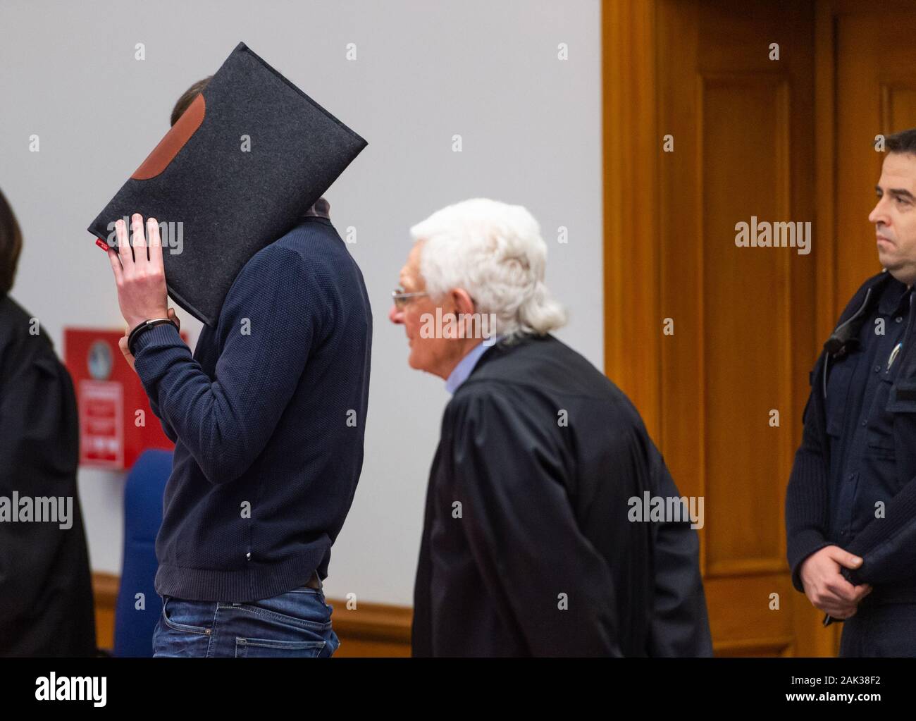 07 January 2020, Lower Saxony, Lüneburg: The defendant (l) stands next to Herbert Lederer (M), his lawyer, in the Lüneburg Regional Court before the start of the trial. The 26-year-old is alleged to have sexually abused several children in Lueneburg and other places as trainer and supervisor of a DLRG local group. Photo: Philipp Schulze/dpa Stock Photo