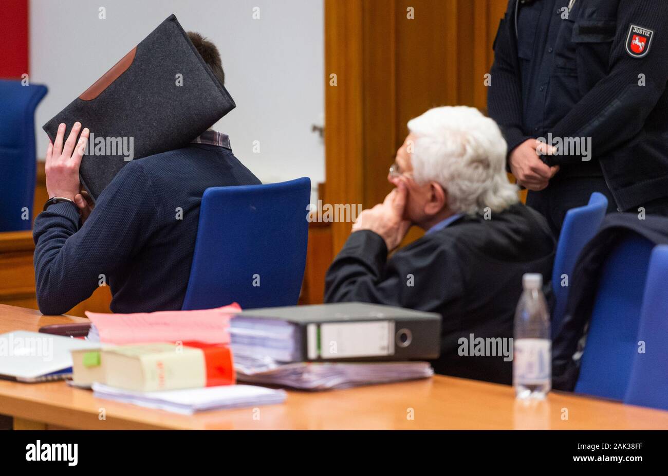 07 January 2020, Lower Saxony, Lüneburg: The defendant (l) sits next to Herbert Lederer (M), his lawyer, in the Lüneburg Regional Court before the start of the trial. The 26-year-old is alleged to have sexually abused several children in Lueneburg and other places as trainer and supervisor of a DLRG local group. Photo: Philipp Schulze/dpa Stock Photo