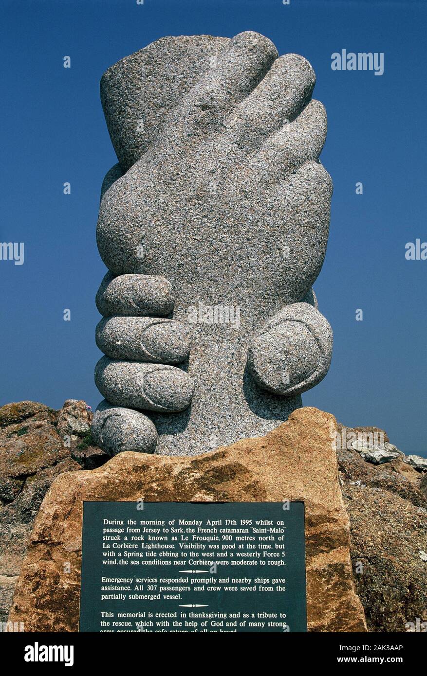 Two hands made from granite remind at the Corbiere Lighthouse near La Pulente in the west of the island of Jersey of a ferry disaster that happened in Stock Photo
