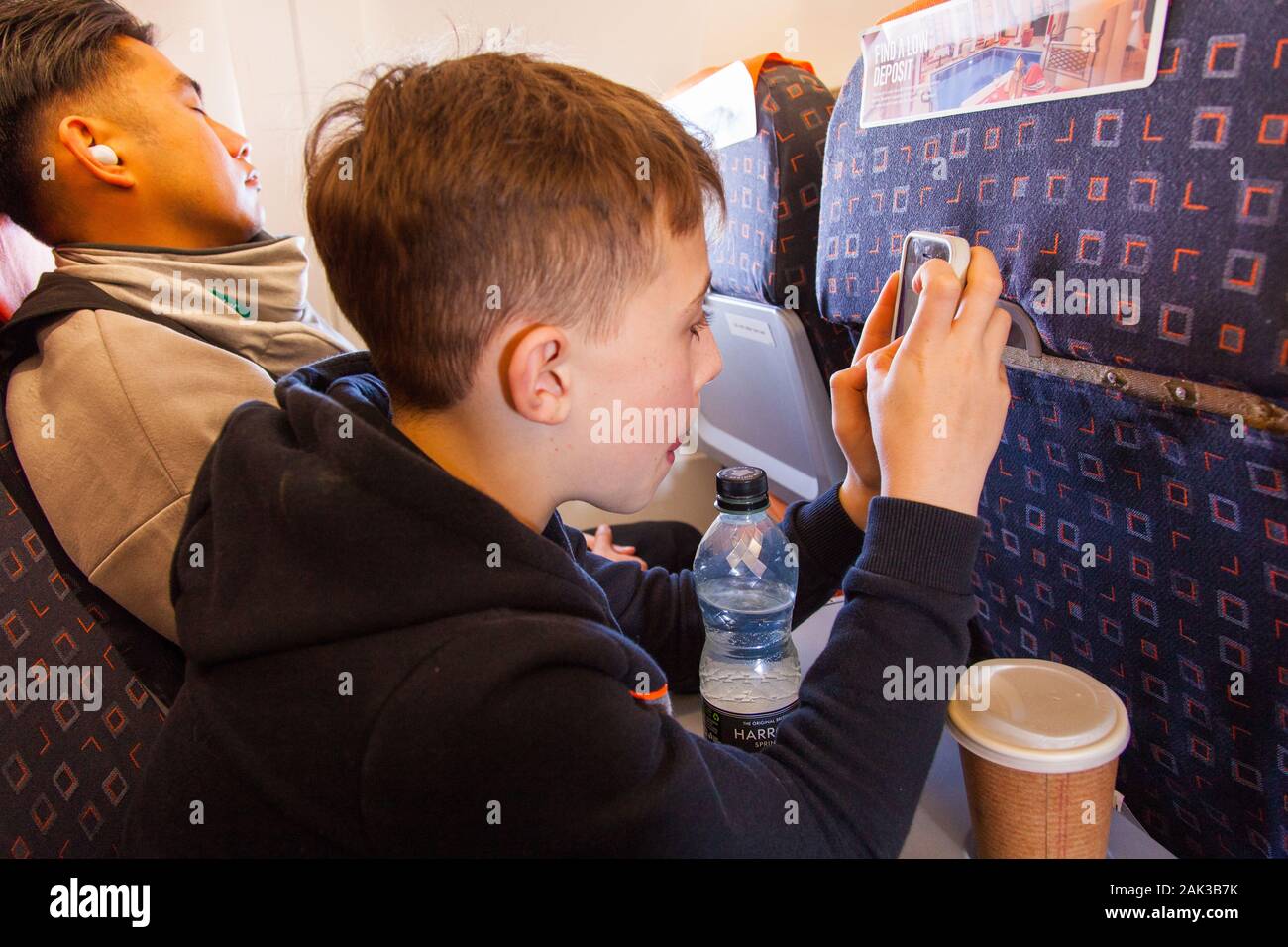 Ten year old boy on his phone, on a easyJet flight to Vienna, London Gatwick Airport, United Kingdom. Stock Photo