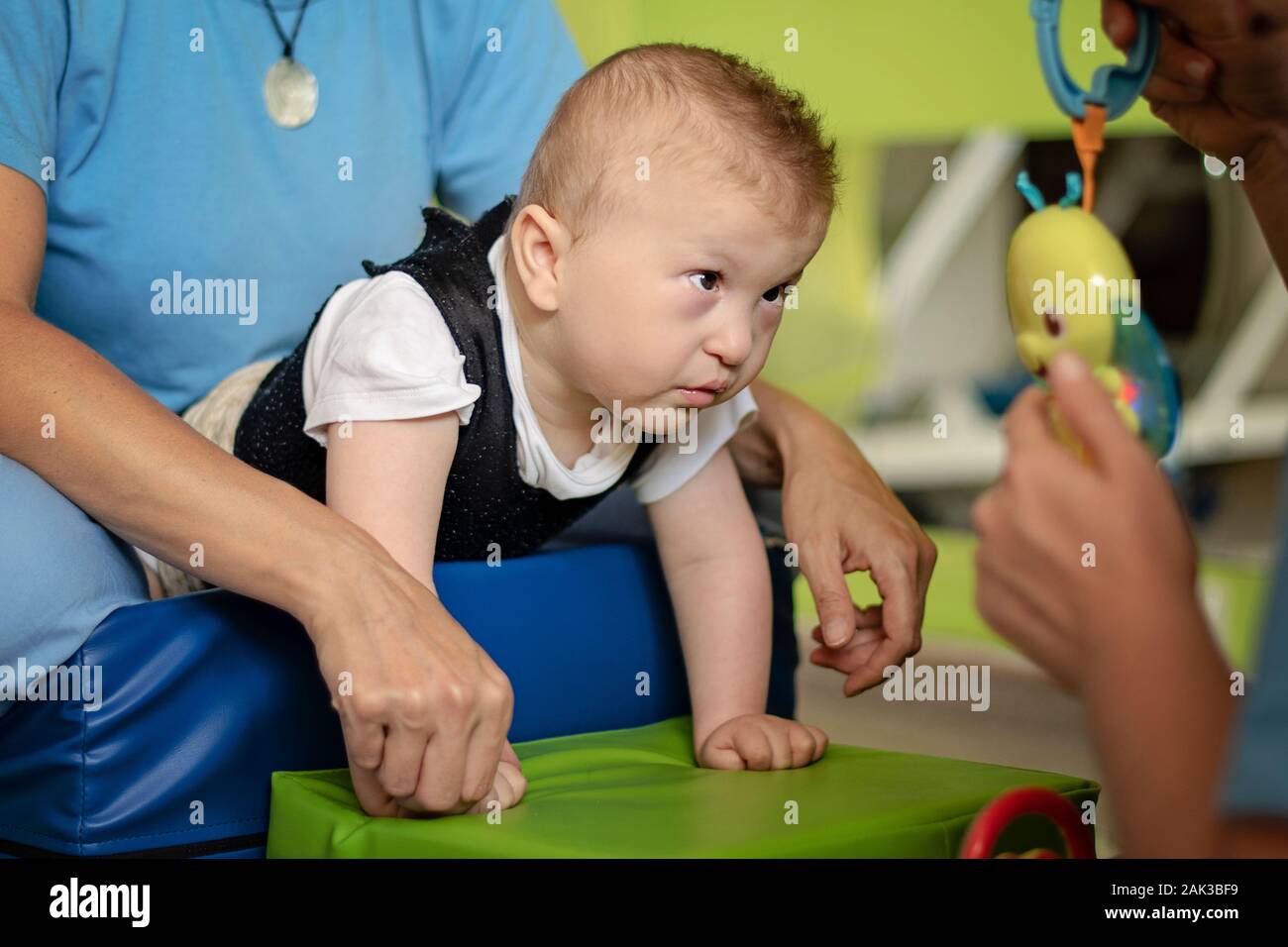Portrait of a baby with cerebral palsy on physiotherapy in children therapy center. Boy with disability has therapy by doing exercises. Special needs. Stock Photo