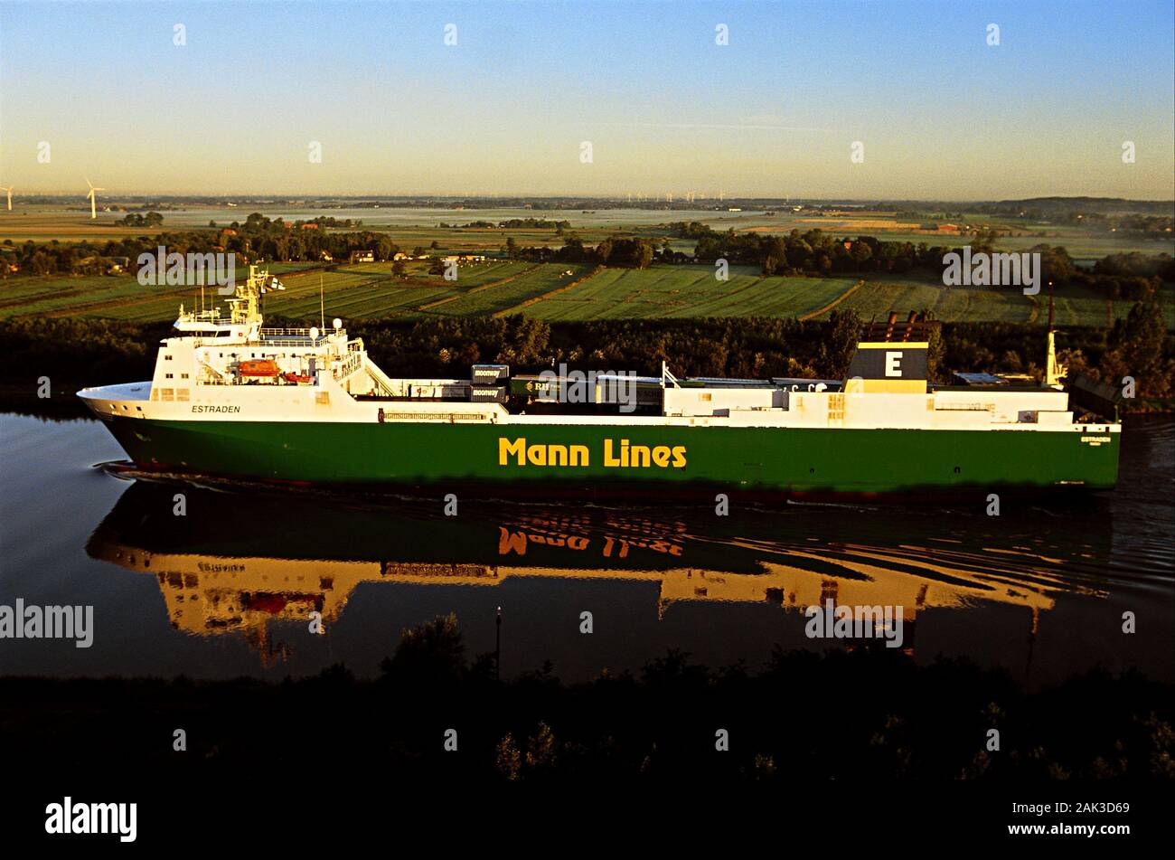 A cargo ship reflecting in the water of the Kiel Canal near Kudensee. Kudensee is located in the federal state of Schleswig Holstein in the North of G Stock Photo