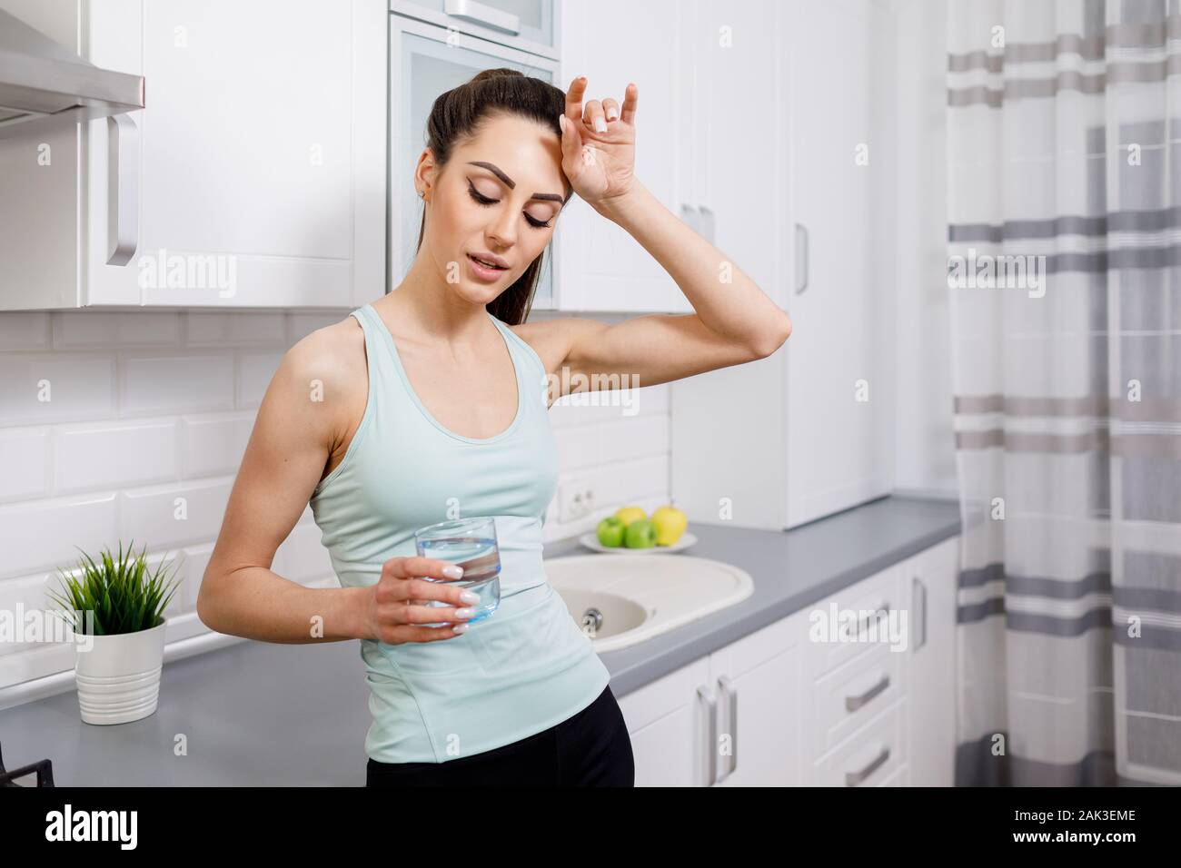Young Woman Drinking and Dry Her Sweaty Forehead Stock Photo