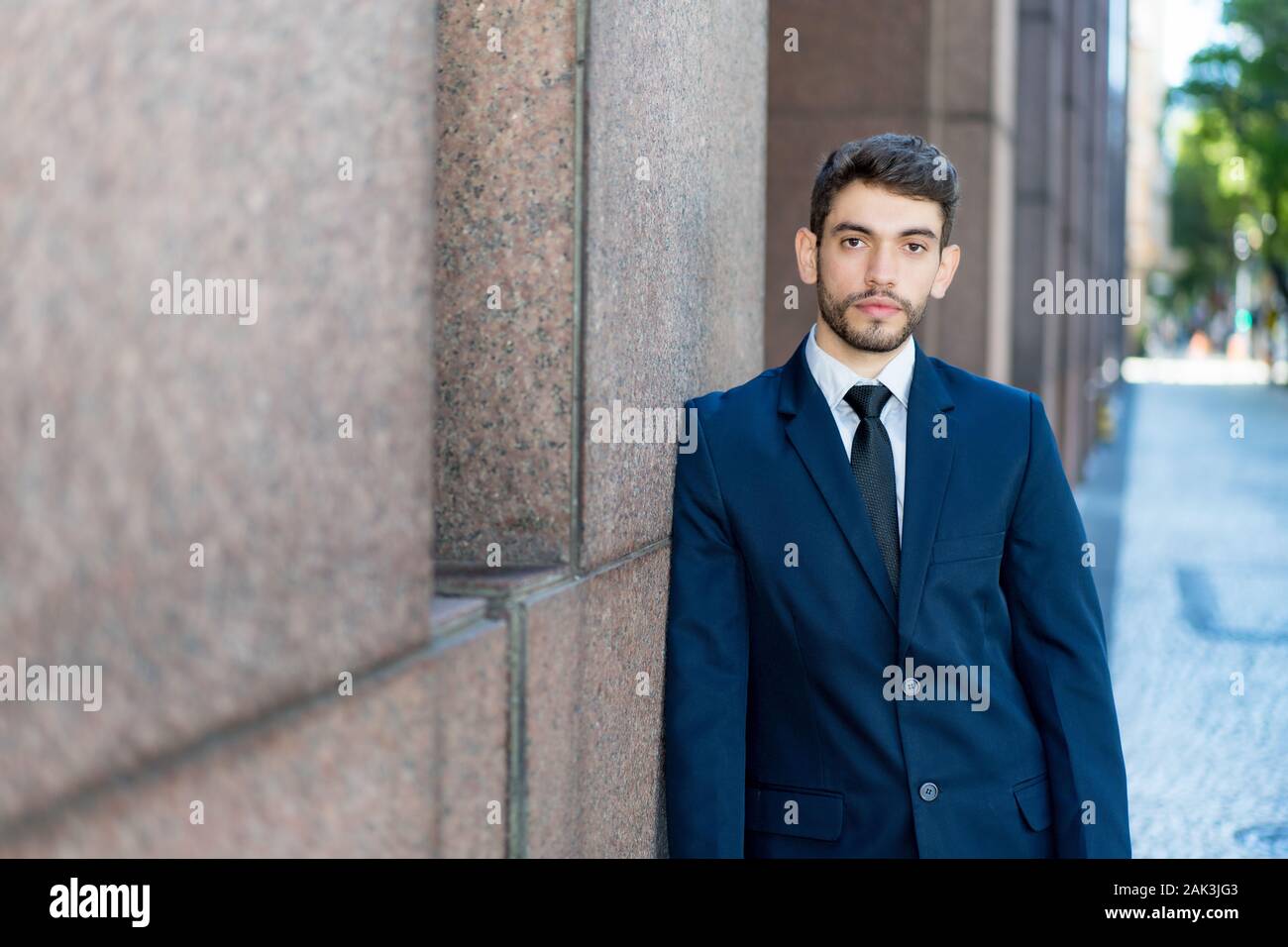 Handsome hipster businessman with beard and suit outdoor in summer in city Stock Photo